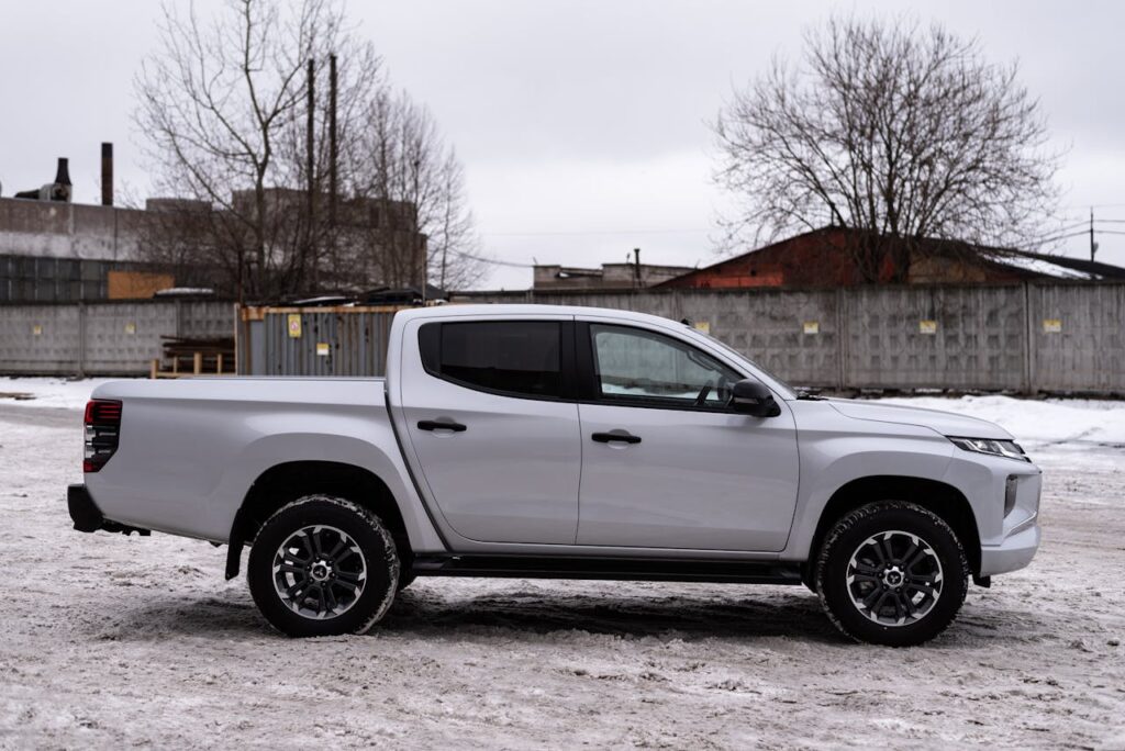 Side view of a modern pickup truck on a snowy urban background, showcasing its design.